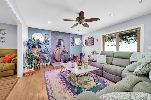 living area with ceiling fan, light wood-style flooring, a wood stove, and recessed lighting