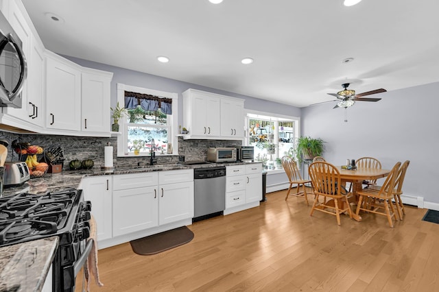 kitchen featuring light wood-type flooring, tasteful backsplash, white cabinetry, and stainless steel appliances