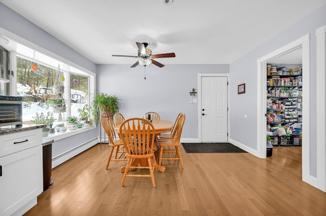 dining space featuring baseboards, a baseboard radiator, a ceiling fan, and light wood-style floors