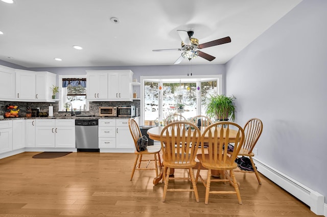 dining room with a baseboard heating unit, light wood-type flooring, ceiling fan, and plenty of natural light