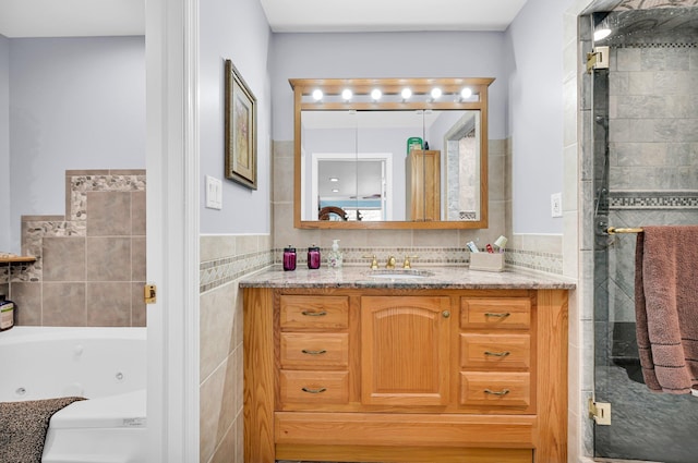 bathroom with a stall shower, vanity, tile walls, and a jetted tub