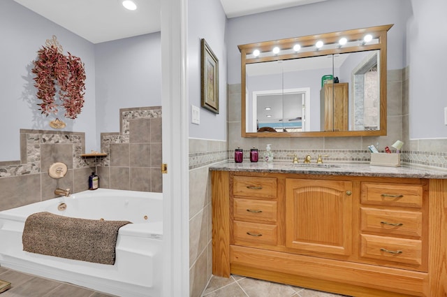 bathroom featuring a jetted tub, tile patterned flooring, vanity, and tile walls