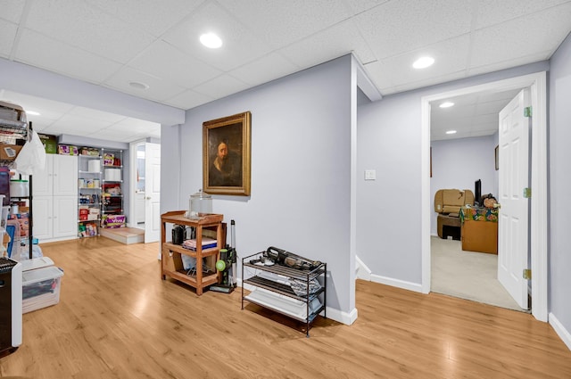 hallway with light wood-type flooring, a drop ceiling, baseboards, and recessed lighting