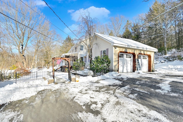 snow covered property featuring a garage and fence