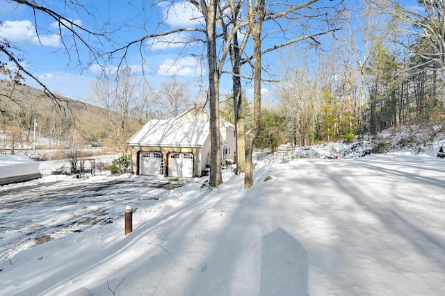 yard covered in snow featuring a detached garage and an outdoor structure