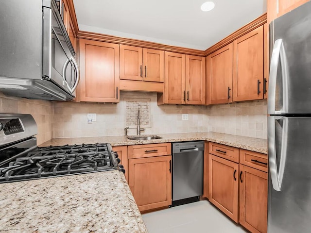 kitchen with light stone counters, stainless steel appliances, sink, and backsplash