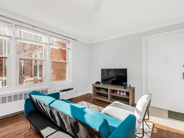 living room featuring hardwood / wood-style flooring, radiator heating unit, crown molding, and an AC wall unit