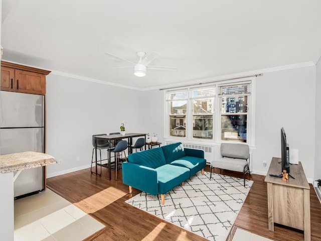 living room featuring radiator, ornamental molding, ceiling fan, and light wood-type flooring