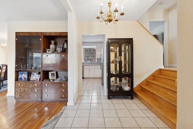 entrance foyer with light tile patterned flooring, crown molding, and a chandelier