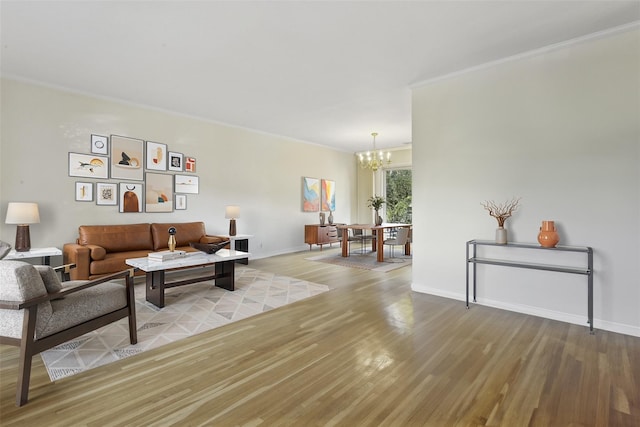 living room featuring ornamental molding, a chandelier, and light hardwood / wood-style floors