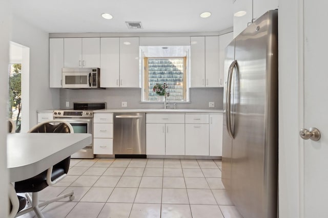 kitchen featuring stainless steel appliances, white cabinetry, sink, and a wealth of natural light