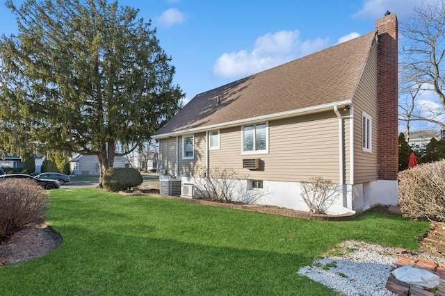 rear view of house featuring central AC unit and a lawn