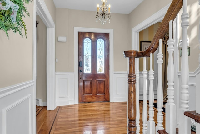 foyer entrance with a baseboard heating unit, a notable chandelier, and light hardwood / wood-style floors