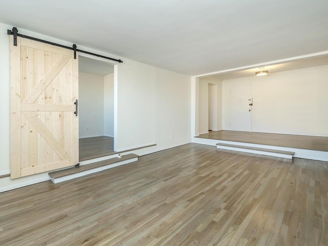 empty room featuring a barn door and hardwood / wood-style floors