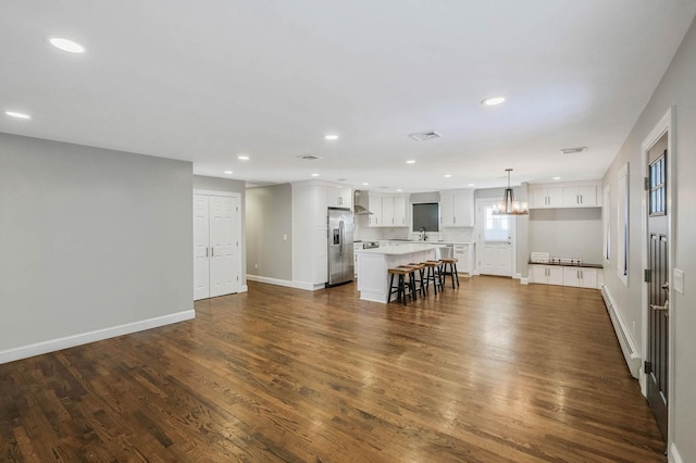 kitchen with a breakfast bar area, white cabinetry, stainless steel fridge with ice dispenser, hanging light fixtures, and a kitchen island