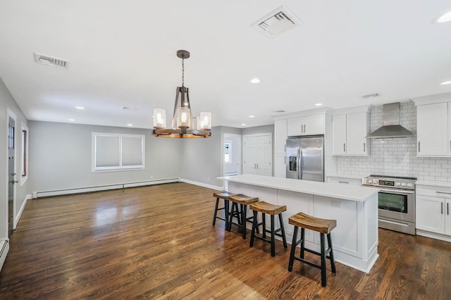 kitchen featuring wall chimney exhaust hood, a kitchen island, white cabinets, stainless steel appliances, and a baseboard heating unit