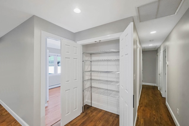 hall with dark wood-type flooring and baseboard heating