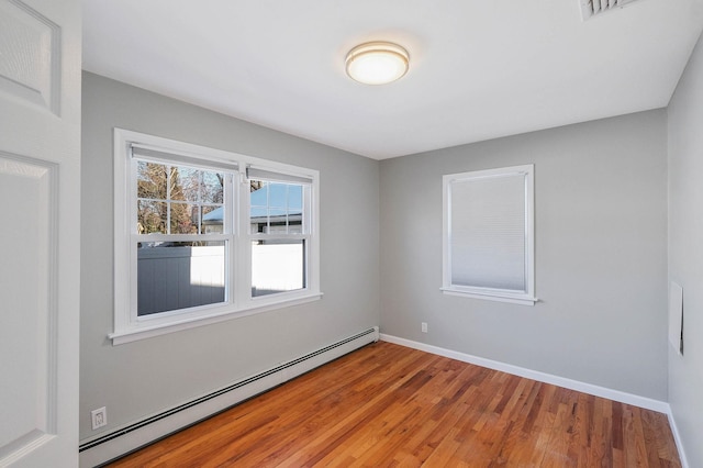 unfurnished room with wood-type flooring and a baseboard heating unit