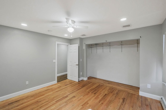 unfurnished bedroom featuring ceiling fan, a baseboard radiator, hardwood / wood-style floors, and a closet