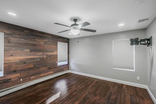 spare room with wooden walls, dark hardwood / wood-style floors, ceiling fan, and baseboard heating