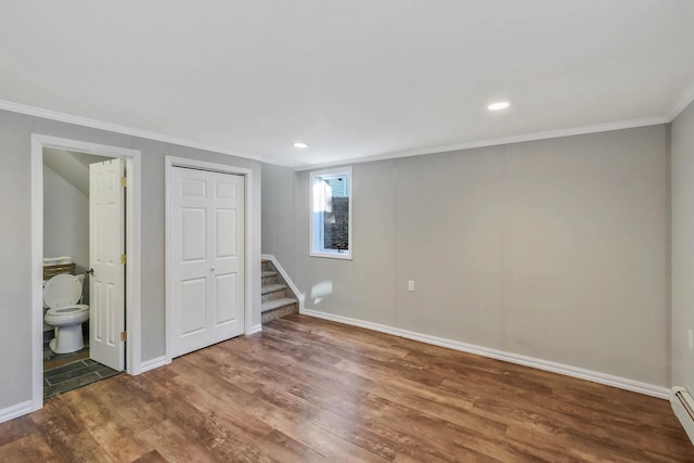 basement featuring crown molding, hardwood / wood-style floors, and a baseboard radiator