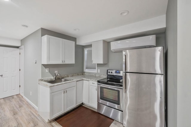 kitchen with sink, light hardwood / wood-style flooring, white cabinets, and appliances with stainless steel finishes