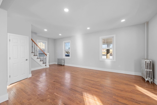 unfurnished living room featuring hardwood / wood-style flooring and radiator heating unit