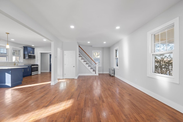 unfurnished living room featuring sink, radiator heating unit, and dark hardwood / wood-style floors