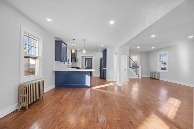 kitchen featuring blue cabinetry, radiator heating unit, a kitchen breakfast bar, and kitchen peninsula