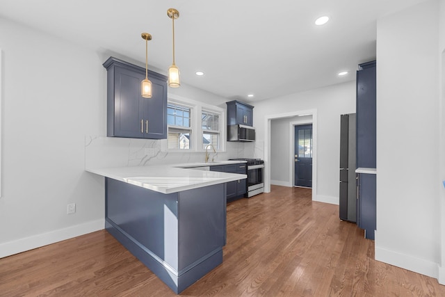 kitchen featuring blue cabinets, a kitchen breakfast bar, decorative backsplash, kitchen peninsula, and stainless steel appliances