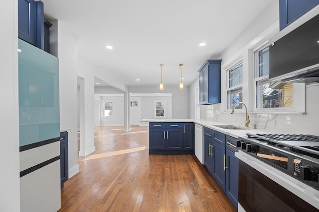 kitchen with blue cabinetry, kitchen peninsula, range with gas cooktop, and pendant lighting