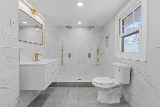 bathroom with vanity, tiled shower, tile walls, and toilet