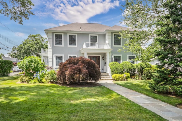 view of front of property with a front lawn, a balcony, and stucco siding