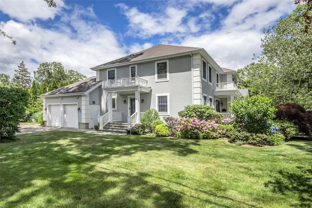 view of front of home with a balcony, driveway, an attached garage, and a front yard