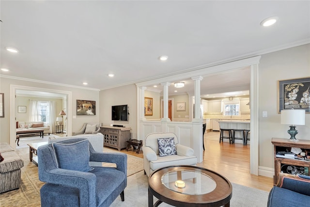 living room featuring ornamental molding, light wood-type flooring, decorative columns, and recessed lighting