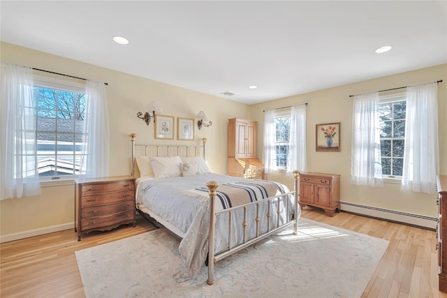 bedroom featuring light wood-style floors, baseboards, baseboard heating, and recessed lighting