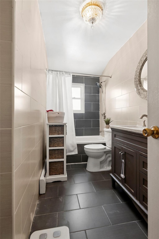 full bathroom with tile walls, tile patterned flooring, vanity, baseboard heating, and toilet