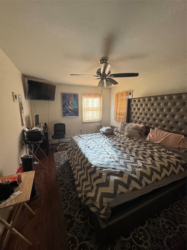 bedroom with ceiling fan, dark wood-type flooring, and a textured ceiling