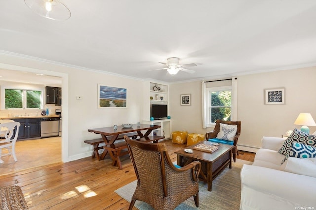 living room featuring ornamental molding, light wood-type flooring, baseboard heating, and built in shelves