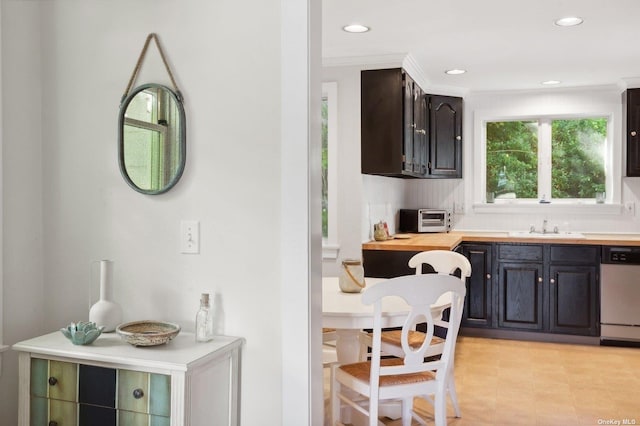 kitchen with crown molding, stainless steel dishwasher, wood counters, and sink