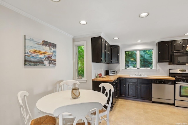 kitchen featuring butcher block countertops, crown molding, sink, stainless steel appliances, and decorative backsplash