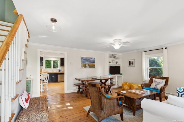 living room featuring crown molding, a baseboard radiator, built in features, ceiling fan, and light hardwood / wood-style floors