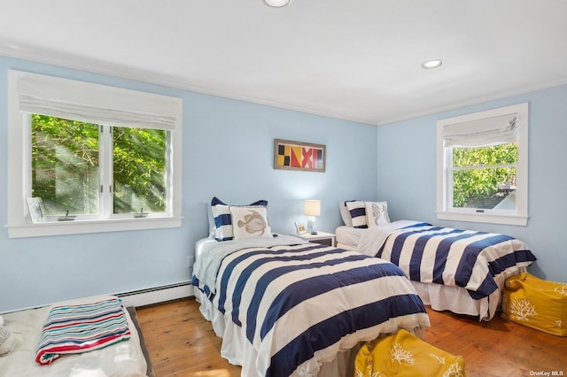 bedroom featuring crown molding, a baseboard radiator, multiple windows, and light hardwood / wood-style flooring