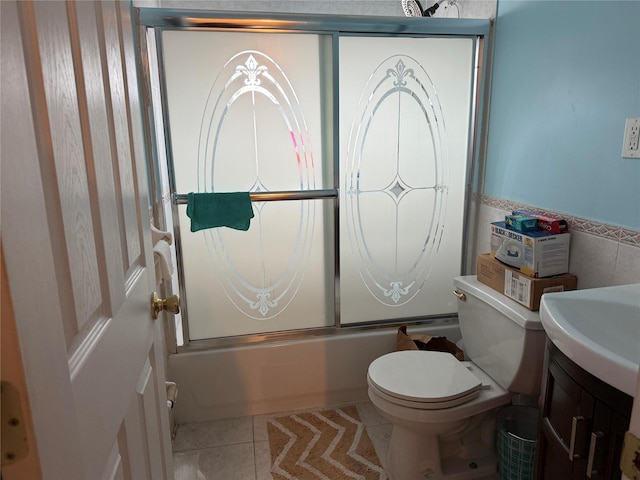 full bathroom featuring shower / bath combination with glass door, tile patterned flooring, tile walls, vanity, and toilet