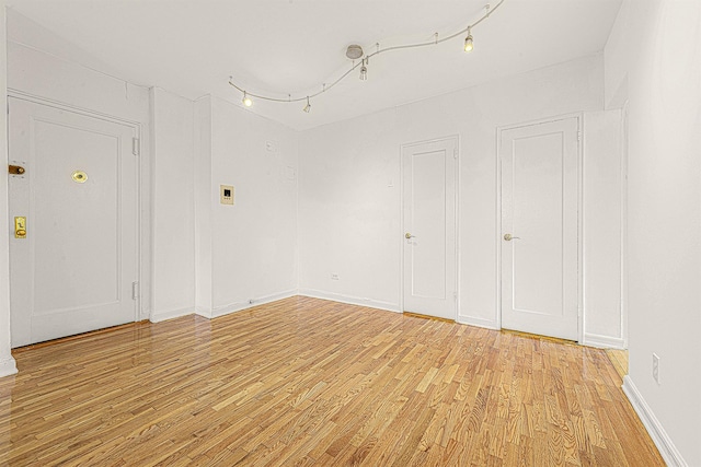 spare room with rail lighting and light hardwood / wood-style floors