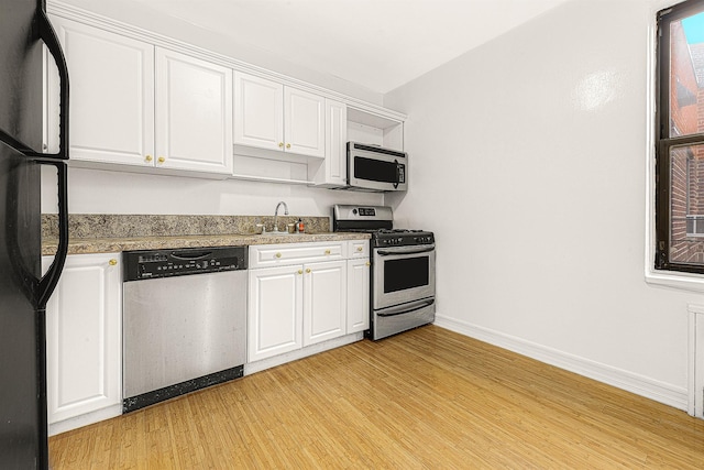 kitchen featuring white cabinetry, appliances with stainless steel finishes, sink, and light wood-type flooring