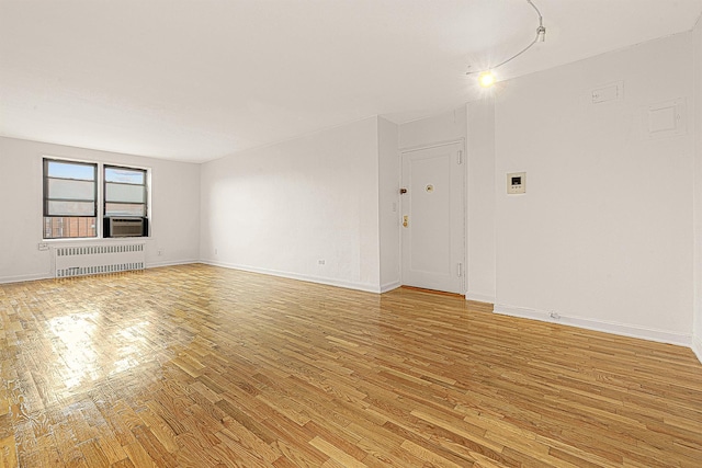 unfurnished living room featuring radiator heating unit and light hardwood / wood-style floors