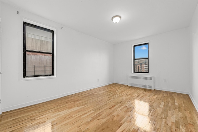 spare room with radiator heating unit and light hardwood / wood-style floors