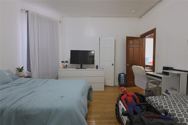 bedroom with crown molding and light wood-type flooring