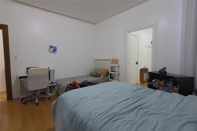 bedroom with ornamental molding and light hardwood / wood-style floors